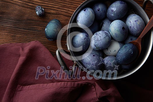 copper pan with eggs and wooden spoon on old wooden background with apron, flat lay