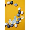eggs and painted feathers on a yellow background, flat lay