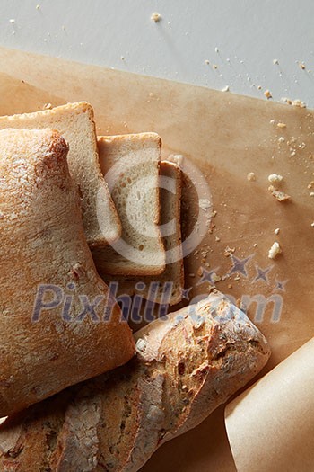 Bread and slices of bread on parchment on a white background, flat lay