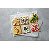 Different types of toast with cheese, vegetables on parchment on a concrete gray background