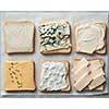 Different kinds of cheeses on toasts on paper close up