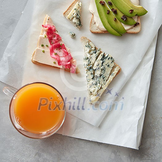 Healthy breakfast concept. Fresh sandwiches with cheese and avocado and glass of juice. Top view Healthy breakfast concept. Fresh sandwiches with cheese and avocado and glass of juice. Top view