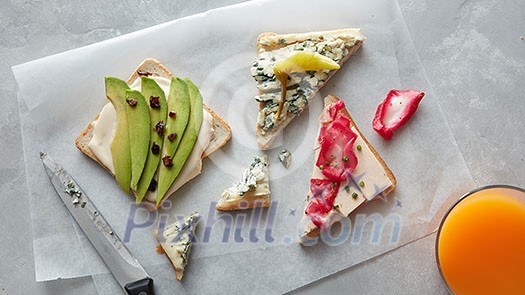 Toasts with cream cheese and avocado placed on paper. Top view