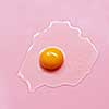 Chicken raw egg yolk over pink background