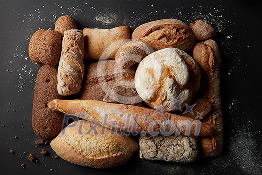 Different kinds of bread represented over black background. Fresh bread after baking: white and brown bread. Collection of wholegrain, sesame, grain, etc. bread. Bakery concept. Different kinds of bread represented over black background. Fresh bread after baking: white and brown bread. Collection of wholegrain, sesame, grain, etc. bread. Bakery concept.