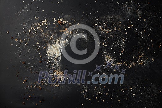 Top view of sprinkled flour and crumbs over black background. Copy space in form of plate may be used for noting your ideas, emotions, feelings.