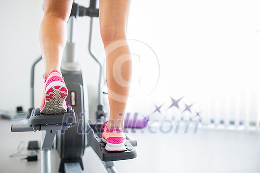 Young woman's muscular legs on stepper/treadmill, closeup