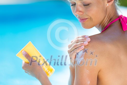 Attractive, young woman with healthy skin applying suncream by a pool (shallow DOF; color toned image)