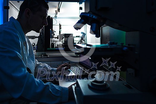 Silhouette of a scientist looking into microscope in a chemistry/physics lab (color toned image) Silhouette of a scientist looking into microscope in a chemistry/physics lab (color toned image)