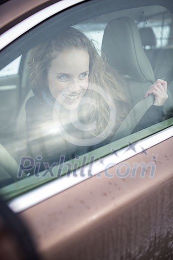 Woman driving a car - female driver at a wheel of a modern car, looking happy, smiling with a relaxed smile (shallow DOF; color toned image) Woman driving a car - female driver at a wheel of a modern car, looking happy, smiling with a relaxed smile (shallow DOF; color toned image)