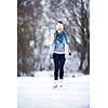 Young woman ice skating outdoors on a pond on a freezing winter day (color toned image; motion blurred image)