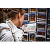 Young woman choosing the right postcard to send home from a vacation abroad (shallow DOF; color toned image)