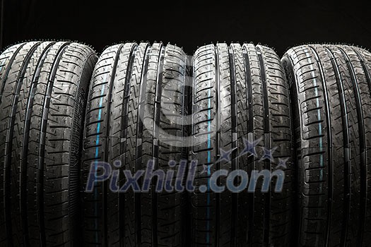 Stack of brand new high performance car tires on clean low-key black studio background