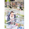Young woman looking for the right pills in a modern pharmacy (shallow DOF; color toned image)
