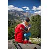 Pretty, female hiker in high mountains packing her backpack