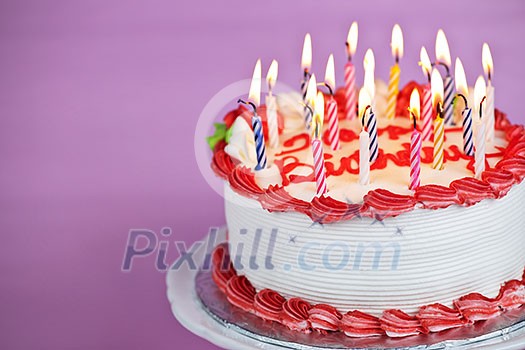 Birthday cake with burning candles on a plate on pink background Birthday cake with burning candles on a plate on pink background