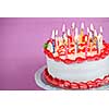 Birthday cake with burning candles on a plate on pink background