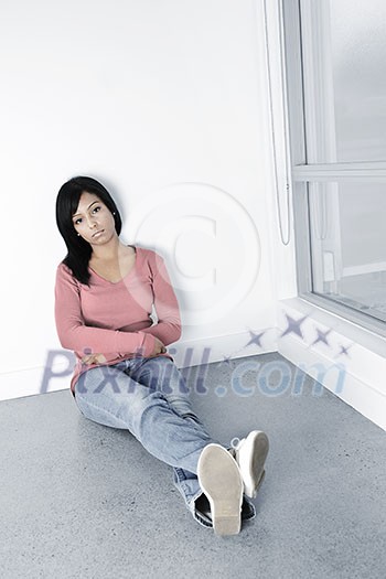 Depressed young black woman sitting against wall on floor