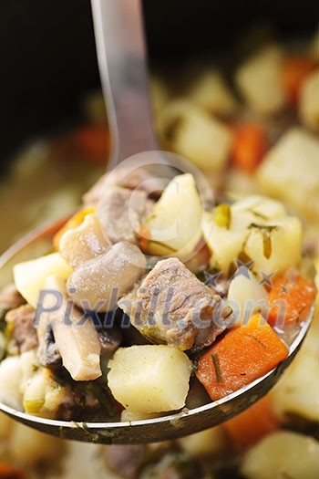 Hearty beef and potatoes stew with vegetables served with ladle Hearty beef and potatoes stew with vegetables served with ladle
