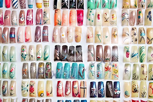 Artificial acrylic nails painted in various designs on display in nail salon Artificial acrylic nails painted in various designs on display in nail salon