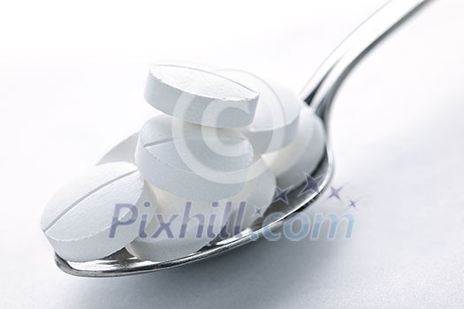 Calcium supplement pills piled on metal spoon closeup Calcium supplement pills piled on metal spoon closeup