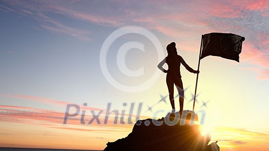 Silhouette of young woman with flag on mountain top