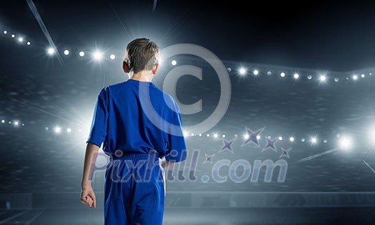 Rear view of kid boy in blue uniform on soccer stadium