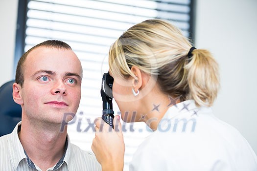 optometry concept - handsome young man having her eyes examined by an eye doctor