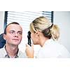 optometry concept - handsome young man having her eyes examined by an eye doctor