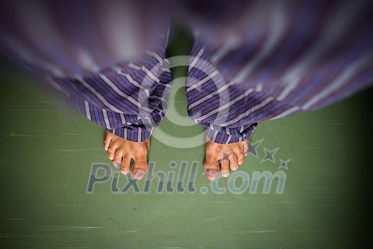 Alone in the house: man in pyjamas looking down on his bare feet Alone in the house: man in pyjamas looking down on his bare feet