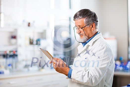 Senior doctor/scientist using his tablet computer at work (color toned image)