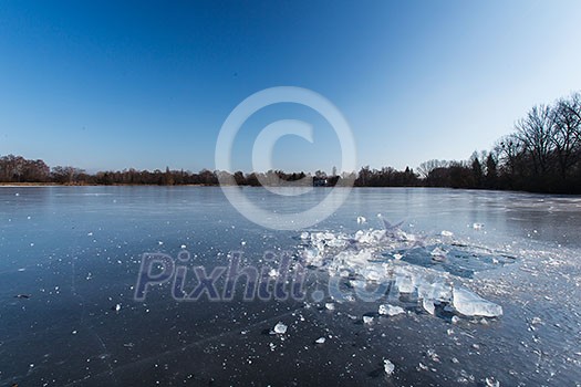 Freezing winter temperatures: block of ice lying on the surface of a frozen pond on a sunny winter day