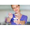 Happy young woman eating yogurt in kitchen