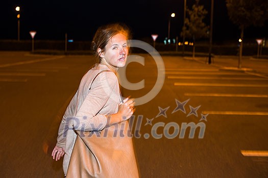 Scared young woman running from her pursuer in a deserted parking lot Scared young woman running from her pursuer in a deserted parking lot