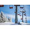 Ski lift with skiers being carried up the hill on a lovely, sunny winter day