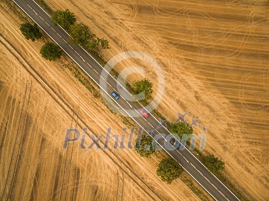 Aerial view of a country road amid fields with a car on it Aerial view of a country road amid fields with a car on it