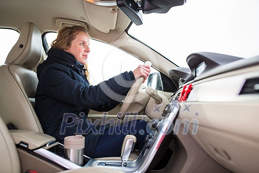 Woman driving a car - female driver at a wheel of a modern car, looking happy, smiling with a relaxed smile (shallow DOF; color toned image) Woman driving a car - female driver at a wheel of a modern car, looking happy, smiling with a relaxed smile (shallow DOF; color toned image)
