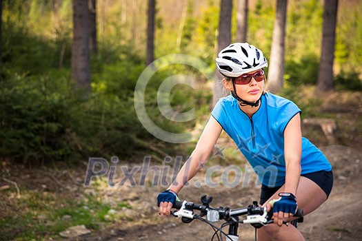 Pretty, young female biker outdoors on her mountain bike (shallow DOF; selective focus)