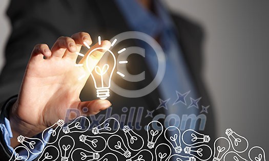 Close up of businesswoman taking glowing light bulb with fingers Close up of businesswoman taking glowing light bulb with fingers