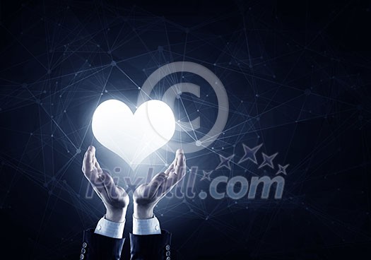 Businessman hands on dark background holding with care digital heart Businessman hands on dark background holding with care digital heart