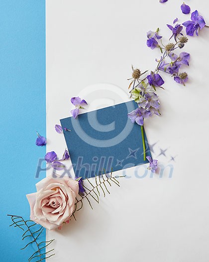 greeting card of purple flowers and blue paper on a white background, flat lay