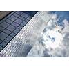clouds reflected in windows of modern office building