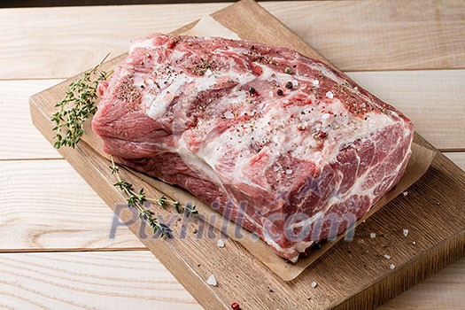 Photo of raw meat. Pork neck with herbs and green thyme on wooden board. Top view Photo of raw meat. Pork neck with herbs and green thyme on wooden board. Top view