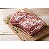 Photo of raw meat. Pork neck with herbs and green thyme on wooden board. Top view