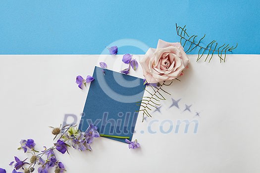 Happy spring lettering. Greeting blue card with blank space and flowers around. Top view, flat lay Happy spring lettering. Greeting blue card with blank space and flowers around. Top view, flat lay