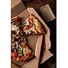 Top view of pieces of cheese pizza in paper box over wooden table
