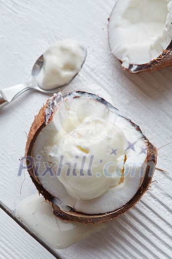 Ice cream in a half of coconut with a spoon On white wooden background