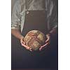 Man hands holding round dark bread, blurred background