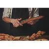 Men's hands hold a baguette with poppy seeds and a table with different breads