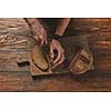 Baker cuts freshly baked organic bread on a wooden brown background flat lay